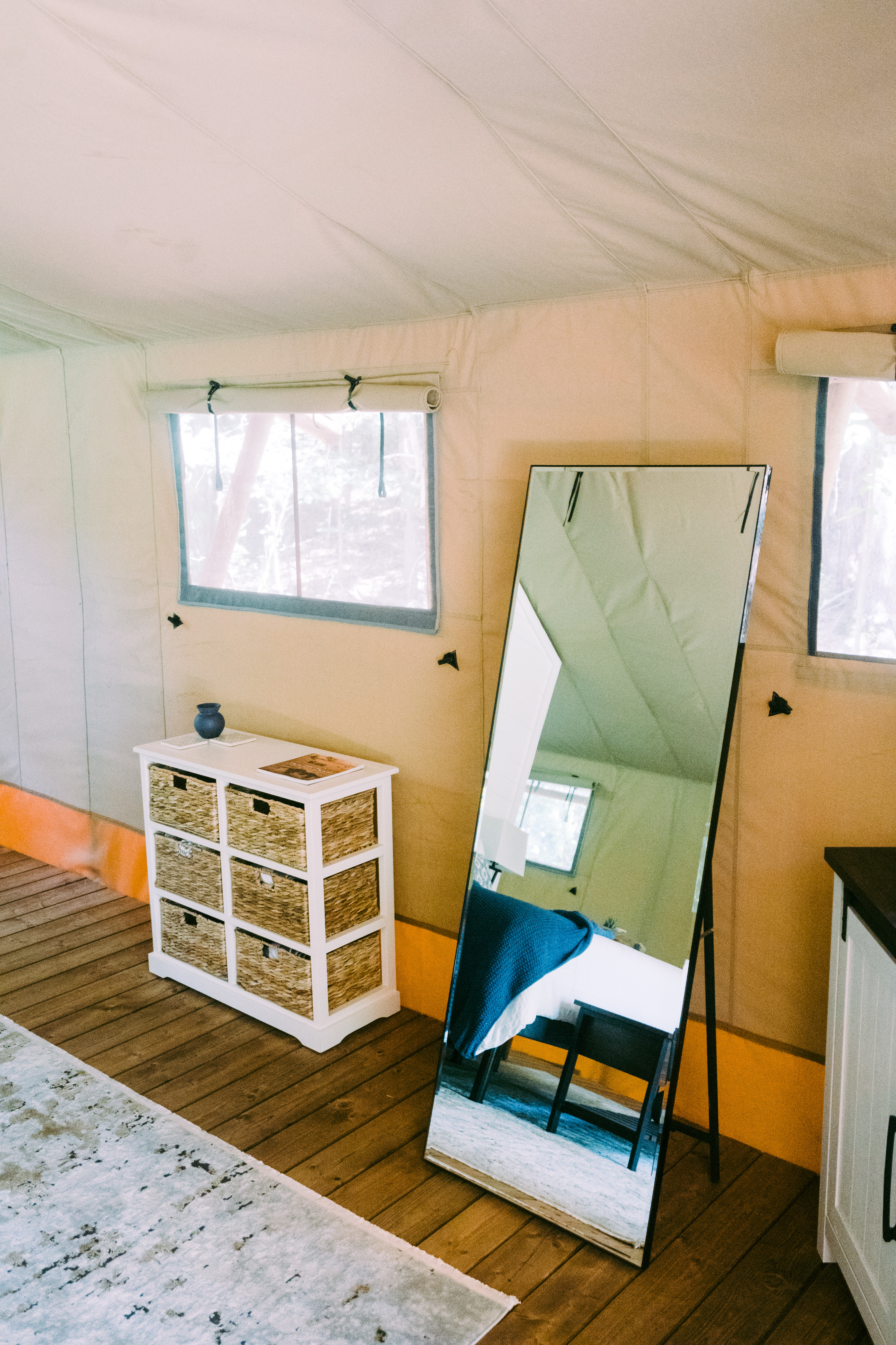 Inside a Dawson's Cove safari tent — canvas walls, wood floor, full-length mirror